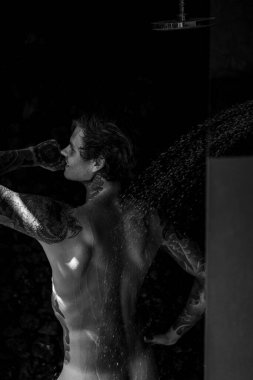 Duşta dövmeli yakışıklı bir genç. yaşam tarzı konsepti. 