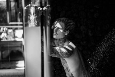 Duşta dövmeli yakışıklı bir genç. yaşam tarzı konsepti. 