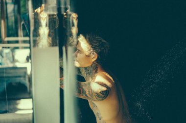 Duşta dövmeli yakışıklı bir genç. yaşam tarzı konsepti. 