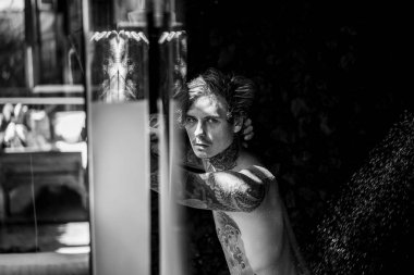 Duşta dövmeli yakışıklı bir genç. yaşam tarzı konsepti. 