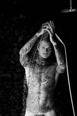 Duşta dövmeli yakışıklı bir genç. yaşam tarzı konsepti. 