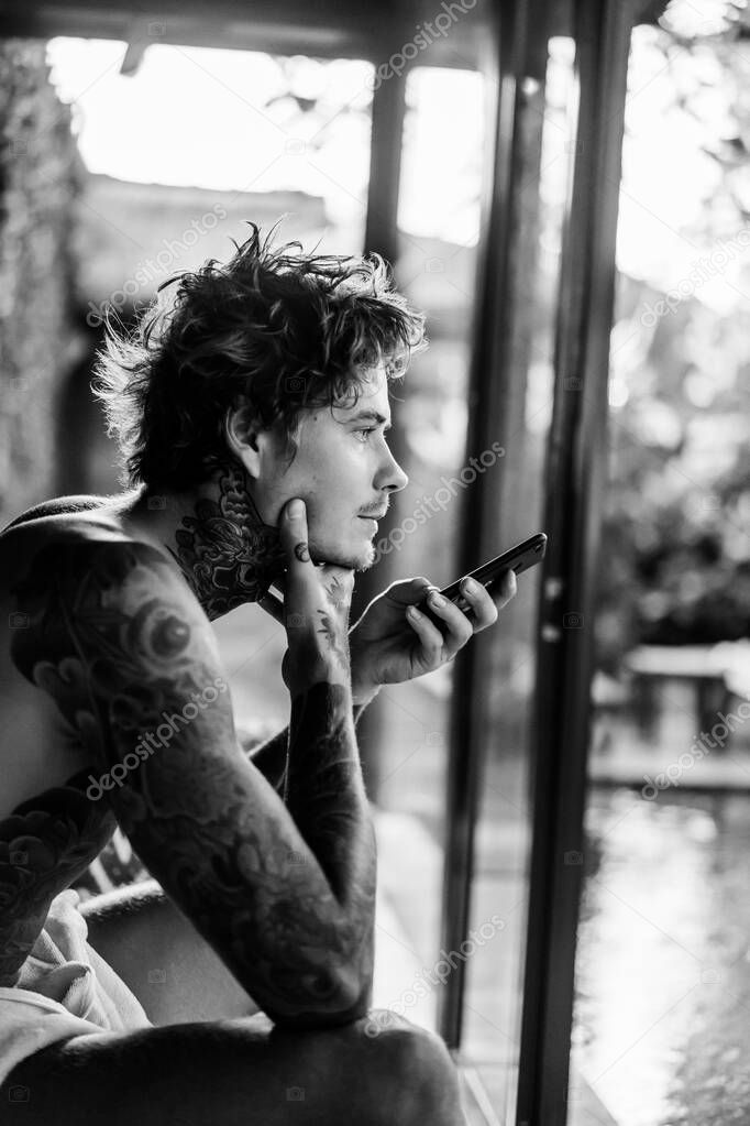 handsome young man in tattoos talking on the phone on speakerpho