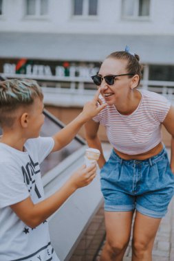 Şehirde çocuklu güzel ve şık bir anne iyi vakit geçiriyor ve dondurma yerken eğleniyor..