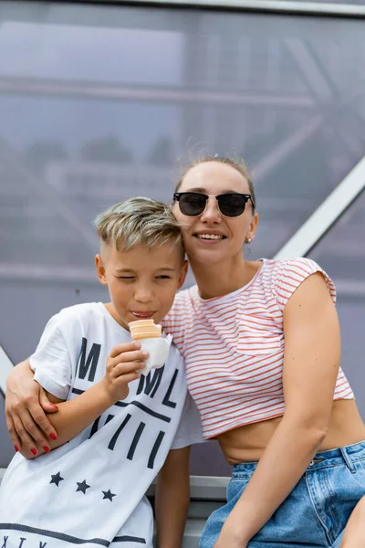 街の子供たちと若い美しいスタイリッシュなお母さんは楽しい時間を過ごしており 楽しいアイスクリームを食べています — ストック写真