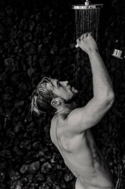 Adam duş alıyor, saçlarını şampuan ürünüyle yıkıyor.