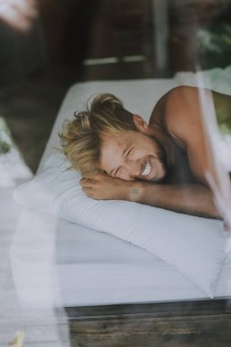 Seksi çıplak genç adam yatakta yatarken kameraya bakıyor. Ka