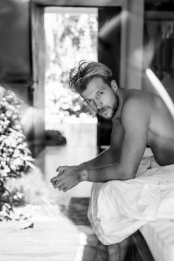 Yatakta yakışıklı bir adam sabah uyanır. Genç adam uyuyor.