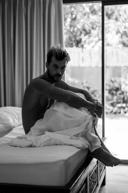 Yatakta yakışıklı bir adam sabah uyanır. Genç adam uyuyor.