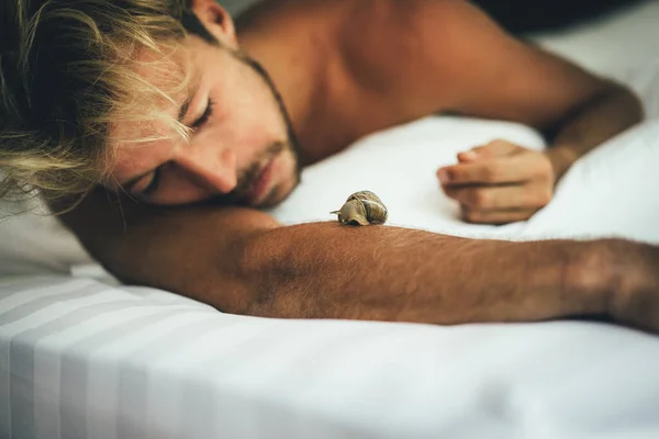 ベッドに寝そべっている間にセクシーな裸の若い男がカメラを見ている — ストック写真