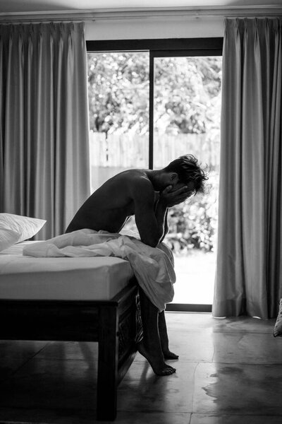 Красивый мужчина в постели просыпается утром. Молодой человек спит