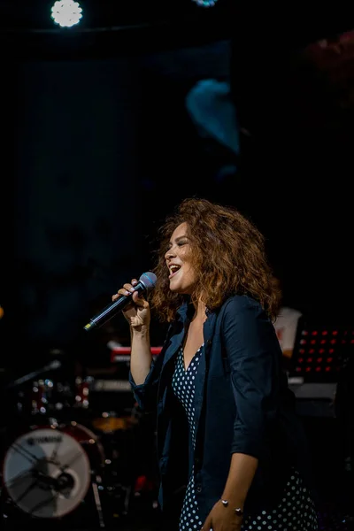 beautiful woman singer on stage singing into microphone