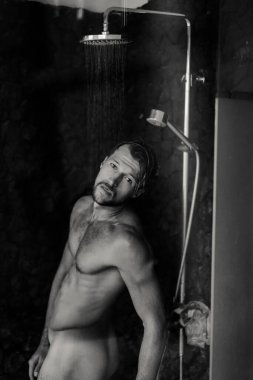 Adam duş alıyor, saçlarını şampuan ürünüyle yıkıyor.