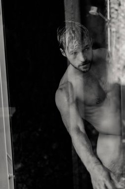 Adam duş alıyor, saçlarını şampuan ürünüyle yıkıyor.