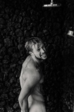 Adam duş alıyor, saçlarını şampuan ürünüyle yıkıyor.