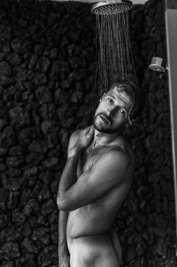 Adam duş alıyor, saçlarını şampuan ürünüyle yıkıyor.