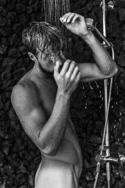 Adam duş alıyor, saçlarını şampuan ürünüyle yıkıyor.