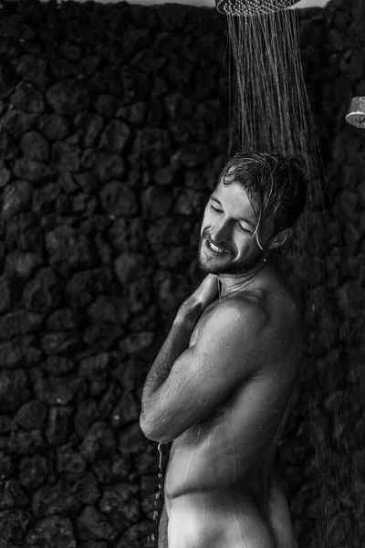 Adam duş alıyor, saçlarını şampuan ürünüyle yıkıyor.