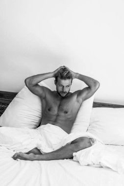 Seksi çıplak genç adam yatakta yatarken kameraya bakıyor. Ka