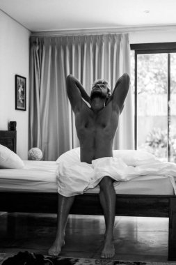 Yatakta yakışıklı bir adam sabah uyanır. Genç adam uyuyor.