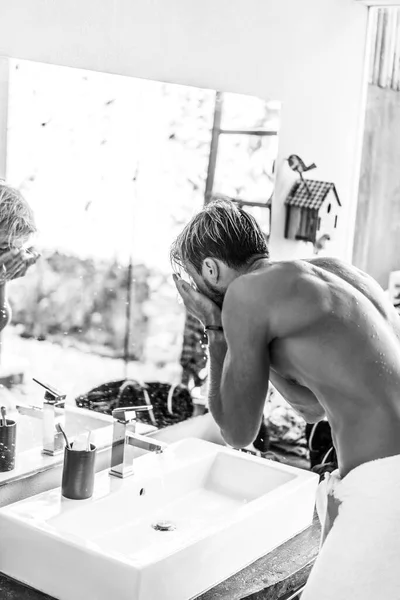 attractive man in the morning in the bathroom brushes his teeth washes his face, morning rituals.