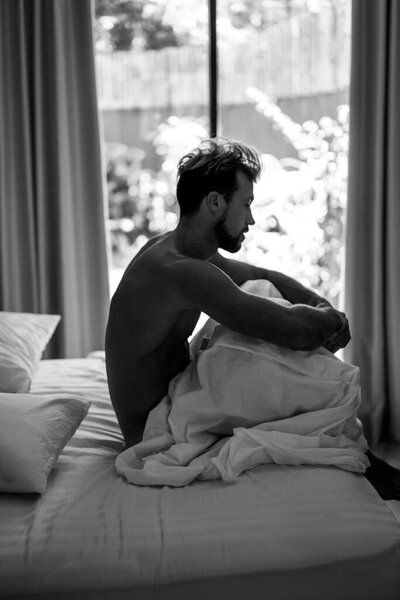 Красивый мужчина в постели просыпается утром. Молодой человек спит