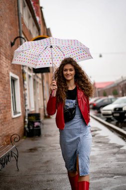 Şemsiyenin altında uzun saçlı, genç ve güzel bir kadın.