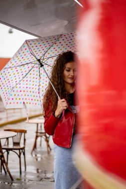 Şemsiyenin altında uzun saçlı, genç ve güzel bir kadın.
