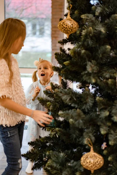 妈妈和孩子们用花环和玩具装饰圣诞树 这家人装饰圣诞树 为圣诞节和新年做准备 孩子们为这棵树感到高兴 — 图库照片