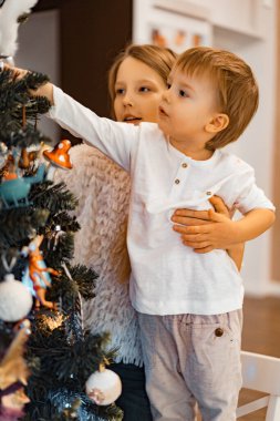 Çocuklar Noel ağacını süsler, erkek ve kız kardeşler tatil için evi dekore ederler. Noel tatili. Mutlu Noeller ve mutlu yıllar konsepti.