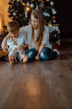 Noel ağacının yanındaki çocuklar, erkek ve kız kardeşler evcil bir fareyle oynuyorlar. Noel tatili. Mutlu Noeller ve mutlu yıllar konsepti.