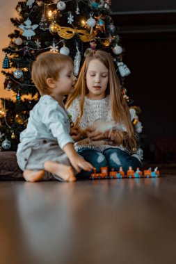 Noel ağacının yanındaki çocuklar, erkek ve kız kardeşler evcil bir fareyle oynuyorlar. Noel tatili. Mutlu Noeller ve mutlu yıllar konsepti.