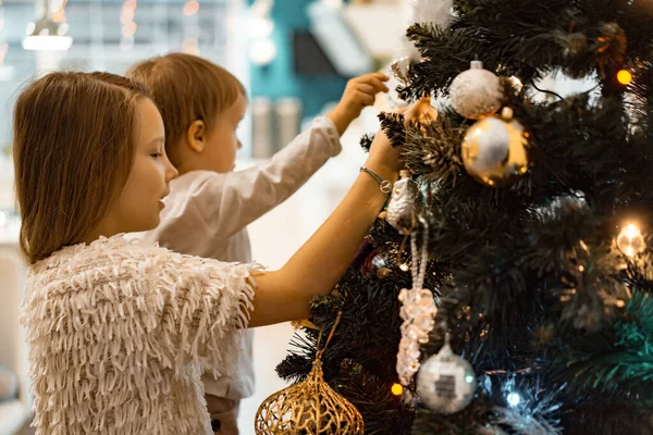 Children decorate the Christmas tree, brother and sister decorate the house for the holidays. Christmas holidays. Merry Christmas and Happy New Year concept.