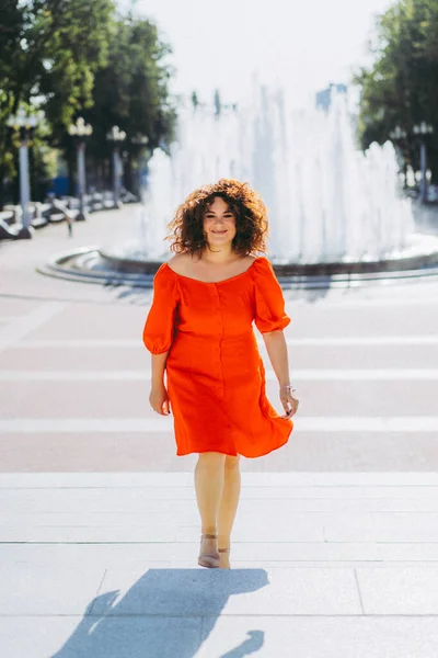 Μια Όμορφη Γυναίκα Σγουρά Μαύρα Μαλλιά Ένα Κόκκινο Φόρεμα Περπατά — Φωτογραφία Αρχείου