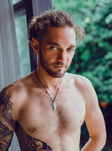 自宅で入れ墨で裸の胴を持つ若い魅力的な男 家の雰囲気の中でセクシーな男の肖像画 — ストック写真
