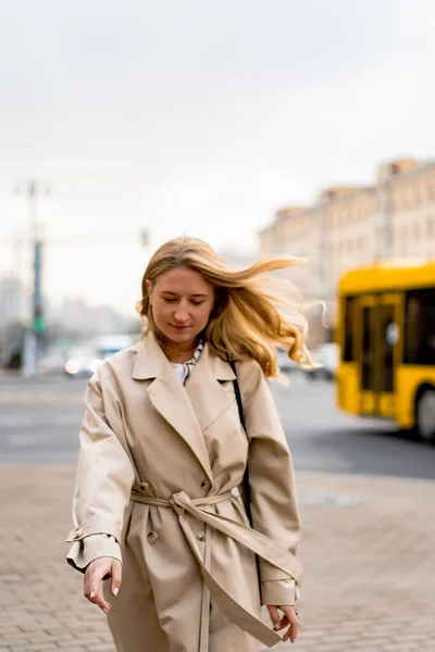 コートを着た美しい若い女性とサングラスが通りを歩いています — ストック写真