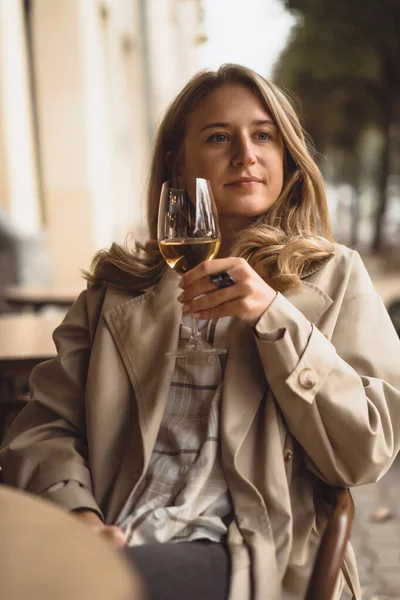 若い美しい女性はワインのガラスとカフェテラスに座っています — ストック写真