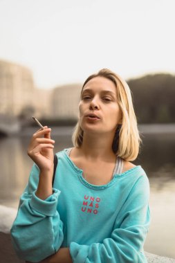 Genç ve güzel bir kadın sigara içiyor. Şehir atmosferi, otomatik