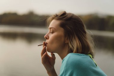 Genç ve güzel bir kadın sigara içiyor. Şehir atmosferi, otomatik