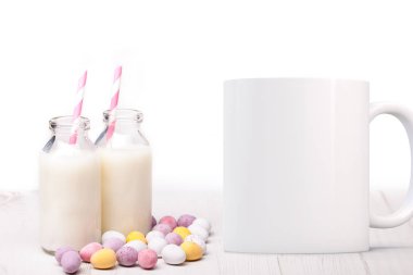 Two mini milk bottles with straws and chocolate mini eggs next to a blank white mug. Perfect for businesses selling mugs, just overlay your quote or design on to the image.
