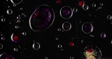 Siyah arkaplanda yağ kabarcıkları hareketinde renk ve parıltı karışımının soyut görünümü