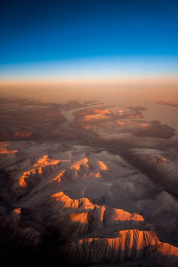 Gün batımında Grönland 'ın buzullarıyla karlı dağların hava manzarası