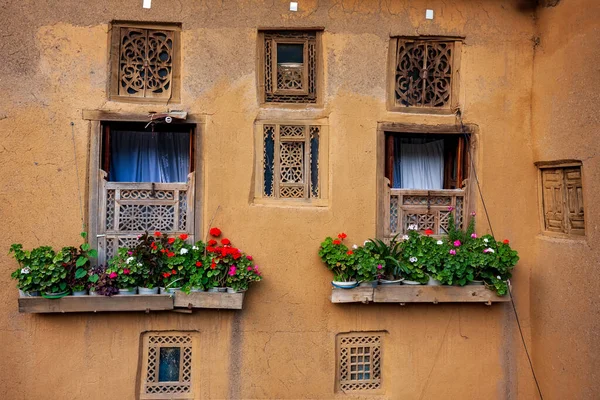 Exterior view of rustic house windows with a flower hanging outside of the building in Masuleh village, Gilan province, Iran