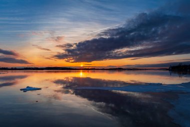Kanada, Prens Edward Adası, Charlottetown 'da gün batımında gölün üzerinde yüzen tek bir donmuş buz örtüsüyle hareketli ve sakin kış manzarası..