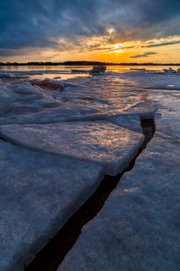 Charlottetown, Prens Edward Adası, Kanada 'da pırıl pırıl bir günbatımında donmuş buz tabakalarıyla bir göl üzerinde yüzen kış manzarası.