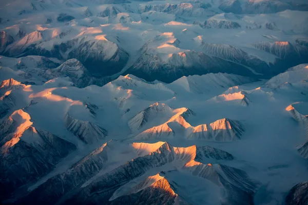 Aerial view of snowy mountain peaks of Greenland during sunset