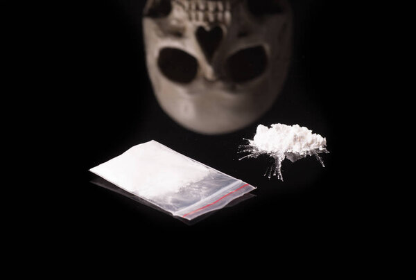 cocaine, Herion or other illegal drugs that are sniffed by means of a tube or injected with a syringe and Skull, isolated on black glossy background