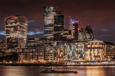 Londra 'nın göbeğinde, Thames nehrinin yanındaki güzel cam bina. Karanlık ve bulutlu gökyüzü ve akan su. Londra 'nın merkezindeki işler.