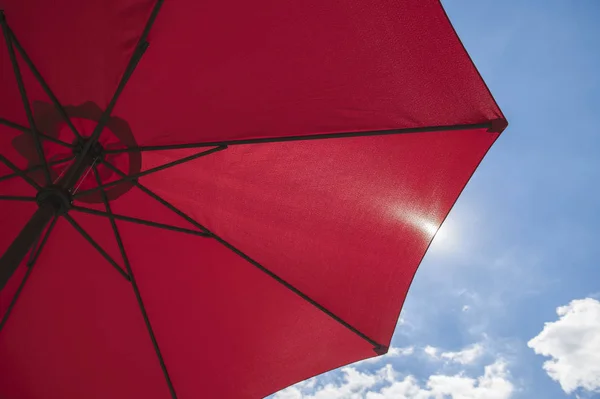 Красный пляжный зонтик на фоне голубого неба — стоковое фото