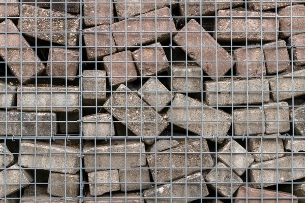 Stone wall built of concrete bricks and metal mesh