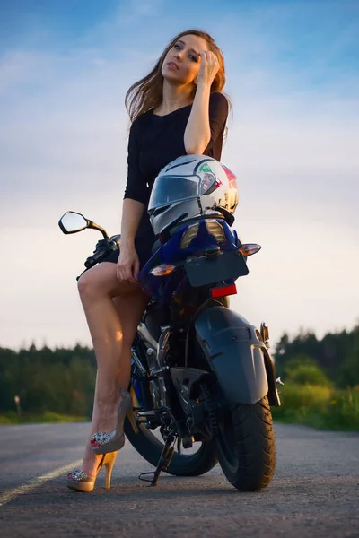 日没でスポーツ バイクに座っている道路上ドレスを着た美しい少女 — ストック写真